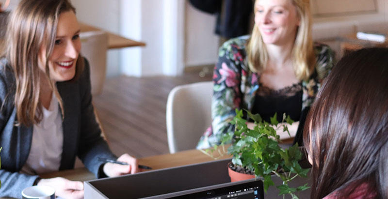 Three women sat around a table in discussion.
